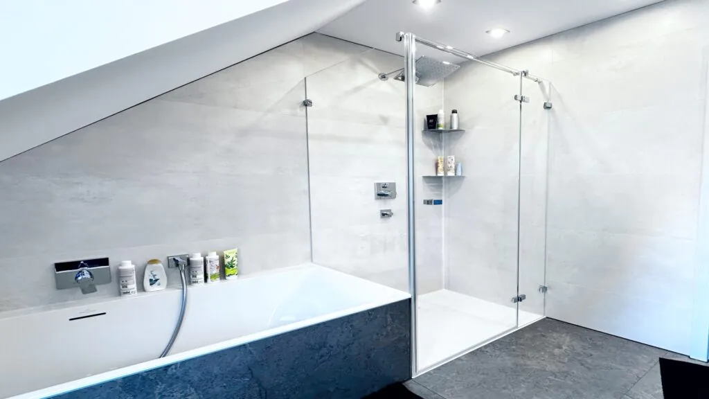 Ganzglasdusche mit Badewannenanschluss und Stabilisierung – funktionell, pflegeleicht und stilvoll dank wasserabweisender Beschichtung.