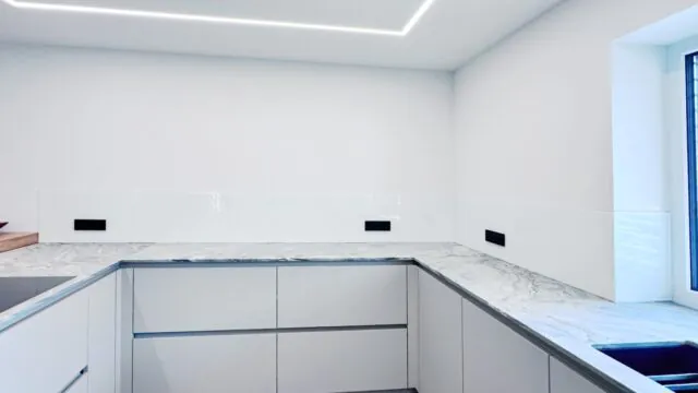 Küchenrückwand aus Sicherheitsglas mit präziser Anpassung an Fensterlaibungen und Steckdosen.