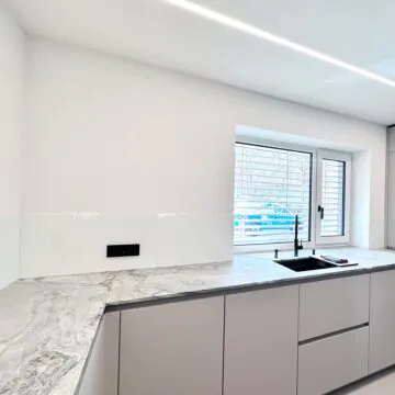Küchenrückwand aus Sicherheitsglas mit Steckdosenausschnitten und integrierten Fensterlaibungen.