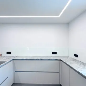 Maßgefertigte Küchenrückwand aus Sicherheitsglas mit präzisen Steckdosenausschnitten und Fensterlaibungen.