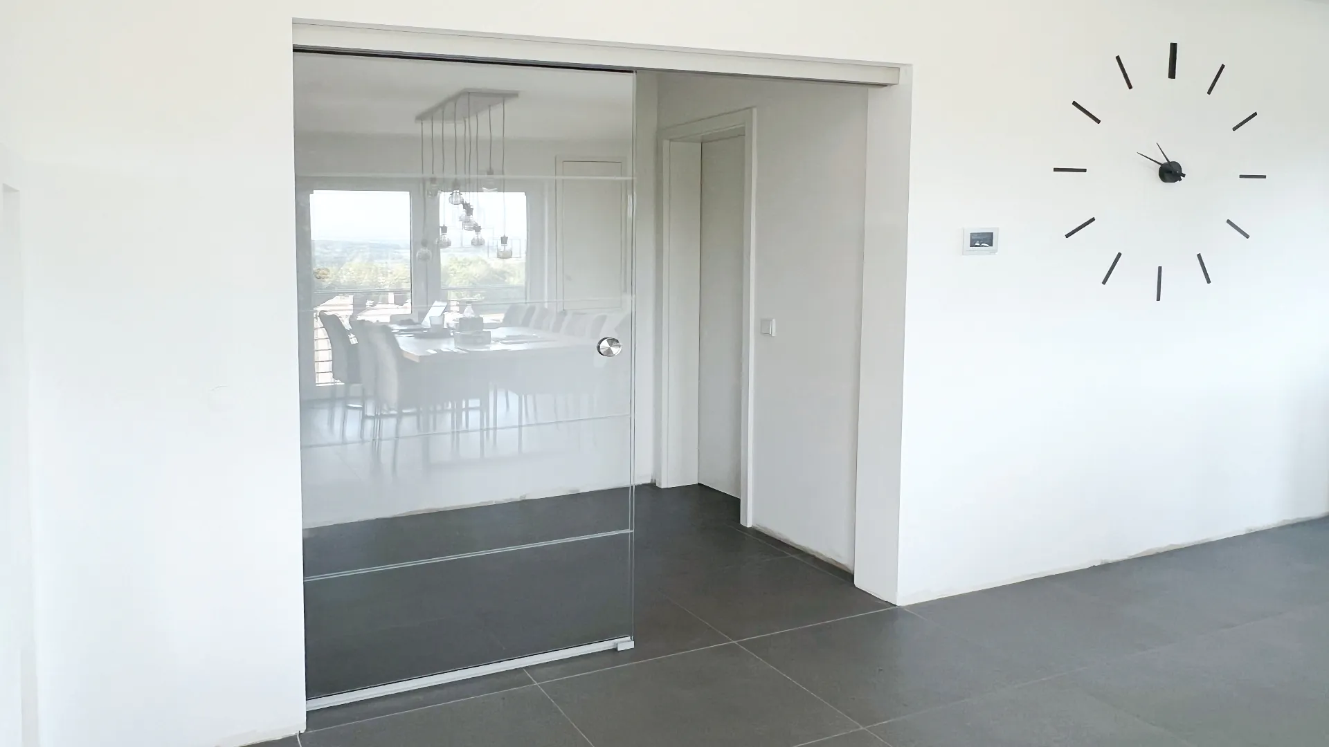 Ganzglasschiebetür mit Seitenteil, Deckenmontage und Sandstrahlstreifen – stilvolle Raumtrennung mit elegantem Design.