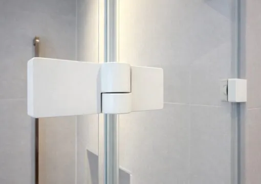 Seitliche Detailansicht eines scharf konturierten Beschlags einer modernen Ganzglasdusche im Badezimmer.