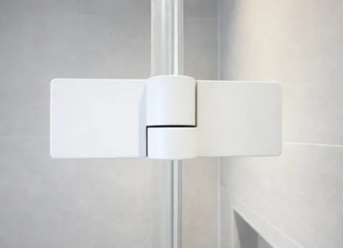Detailaufnahme eines weißen Ganzglasduschen-Beschlags aus mattem Metall an einer klaren Glasdusche.