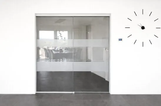 Ganzglasschiebetür mit Seitenteil, Deckenmontage und Sandstrahlstreifen – stilvolle Raumtrennung mit elegantem Design.