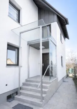 Modernes Glasvordach mit Seitenteil aus Sicherheitsglas und Edelstahlprofilen an einem Hauseingang.